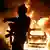 An Israeli policeman gestures as a car burns.