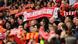 A fan of Liverpool FC holds up a scarf with its musical slogan "You'll never walk alone" printed on it A fan of Liverpool FC holds up a scarf with its musical slogan "You'll never walk alone" printed on it