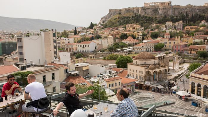 Visiteurs dans un café à Athènes, avec l'Acropole et d'autres bâtiments en arrière-plan