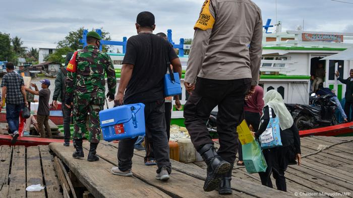 Several men walk down a gangway for a boat