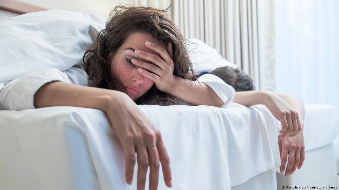 mujer acostada tomándose la cabeza