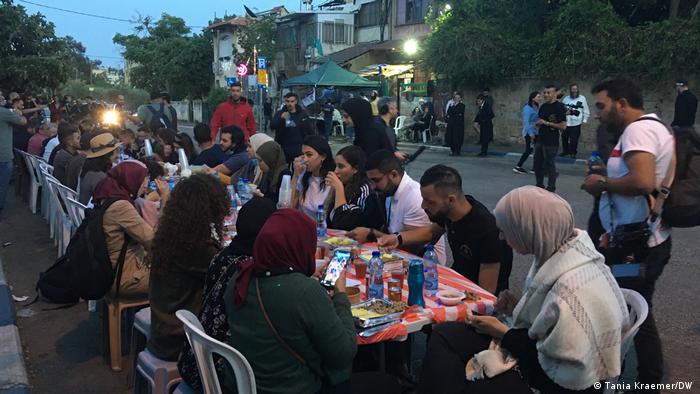 A group of Palestinians sits along a long table breaking their fast outside during Ramadan