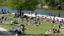 Viele Menschen lagern am Sonntag auf einer Wiese am Ufer der Isar und genießen das sommerlich warme Wetter. +++ dpa-Bildfunk +++