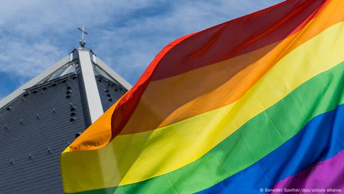 A rainbow flag near a church spire