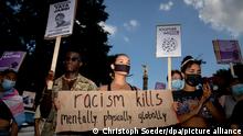 Eine Teilnehmerin einer Demonstration unter dem Motto «Deutschland hat ein #Rassismusproblem – Aktionswochenende gegen Polizeigewalt» hält vor der Siegessäule ein Schild mit der Aufschrift „Racism kills, mentally, physically, globally“ (Rassismus tötet, psychisch, physisch, global).