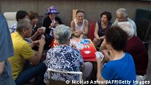 In this picture taken on July 4, 2017 elderly people play cards on a street in Shenyang. While foreign firms complain about being locked out of large swathes of China's vast market, the door has cracked open a bit wider in Liaoning province as the authorities seek to revive the recession-hit industrial region.
(Photo credit should read NICOLAS ASFOURI/AFP via Getty Images)