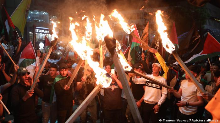 Palestinians light torches during a protest against attacks by Israeli police