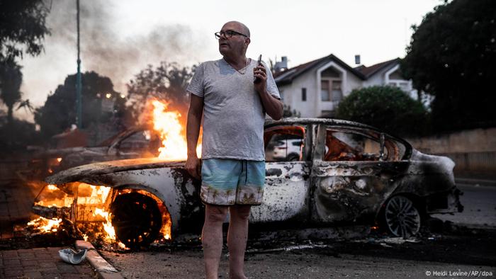 Um morador judeu de Lod ao lado de seu carro em chamas durante confrontos com árabes israelenses e a polícia em 11 de maio de 2021. Um morador judeu de Lod ao lado de seu carro em chamas durante confrontos com árabes israelenses e a polícia em 11 de maio de 2021.