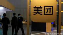 FILE - In this April 30, 2021, file photo, workers walk by the logo of Meituan during an Internet Technology Expo in Beijing. Shares in Meituan, Chinaâ€™s largest food delivery platform, have tumbled Tuesday, May 11, 2021 after its CEO posted -and then deleted - an ancient poem in a move widely seen as criticism of the Chinese government. Authorities are investigating the company over allegations of anti-monopolistic behavior, part of a wider crackdown on technology companies. (AP Photo/Ng Han Guan, File)