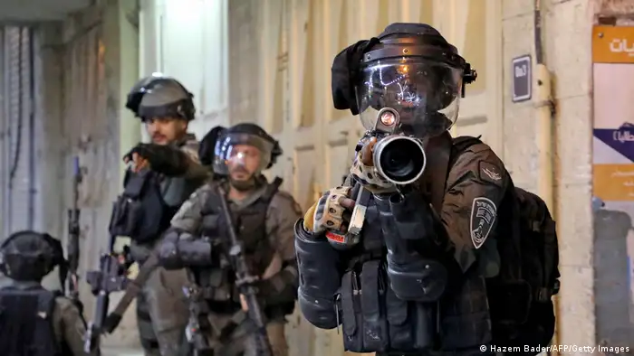 Israeli security forces position themselves against demonstrators with heavy weaponry