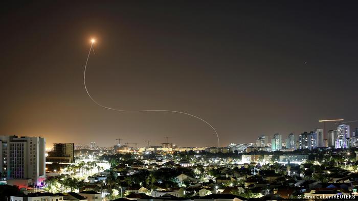 A streak of light above a city at night as rockets are intercepted