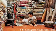 Zwei Kinder haben es sich auf Teppichen eines Teppichgeschäfts auf einem großen Markt in der Hauptstadt des Uigurischen Autonomen Gebietes Xinjiang. +++ dpa-Bildfunk +++