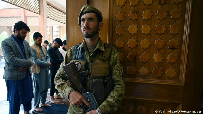Ein bewaffneter Sicherheitsmann steht in einer Moschee neben betenden Männern