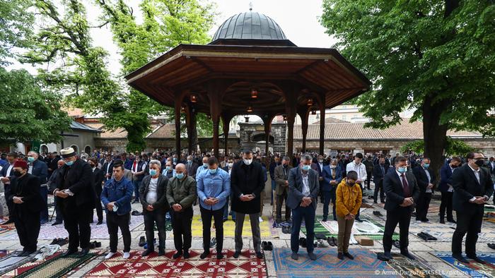 Männer stehen in Reihen auf dem Vorplatz einer Moschee
