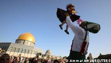 A clown plays with a young girl during Eid al-Fitr prayers, which mark the end of the holy fasting month of Ramadan, at the compound that houses al-Aqsa mosque, known to Muslims as Noble Sanctuary and to Jews as Temple Mount, in Jerusalem's Old City, amid Israel-Gaza fighting May 13, 2021. REUTERS/Ammar Awad