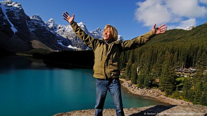 A woman stands on a rock above Moraine Lake in Banff, Canada A woman stands on a rock above Moraine Lake in Banff, Canada