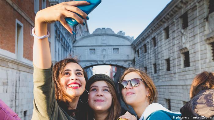 Three young women take a selfie in front of the Bridge of Sighs in Venice