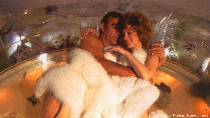 Schauspieler Sean Connery liegt mit einer Frau unter einem weißen Fell