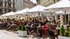 People sitting at outside tables on a square. People sitting at outside tables on a square.