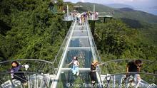 Tourists walk on a 400-meter-long glass-bottomed sky walkway at the Yalong Bay Tropical Paradise Forest Park in Sanya city, south China's Hainan province, 3 September 2018. A 400-meter glass walkway in Yalong Bay Tropical Paradise Forest Park in Sanya, Hainan Province opened to the public at the end of August and became a popular tourist spot immediately. The park is located in the southeast of Sanya and surrounds the Yalong Bay National Tourist Resort, known as the most spectacular bay in the world because of its natural assets.