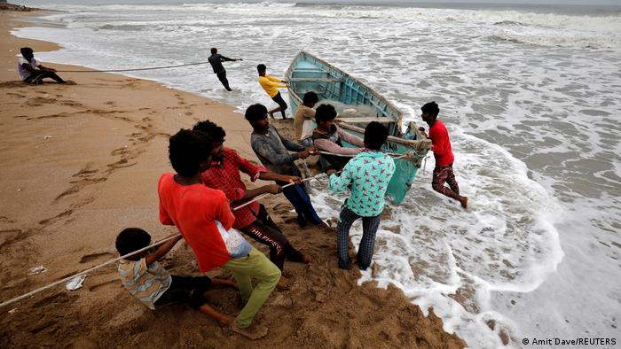 People move a fishing boat to a safer place along the shore ahead of Cyclone Tauktae in Veraval in the western state of Gujarat