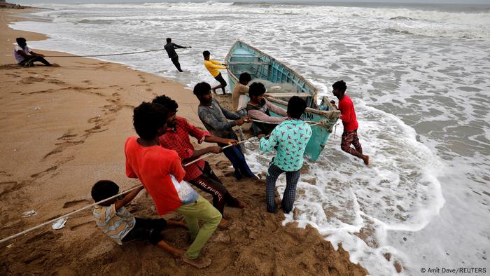 People move a fishing boat to a safer place along the shore ahead of Cyclone Tauktae in Veraval in the western state of Gujarat