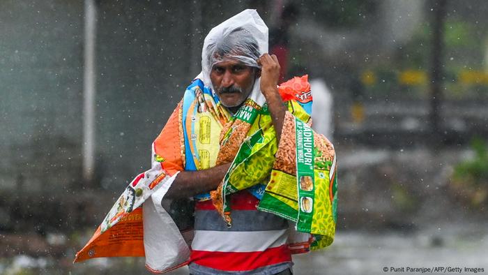 Un hombre se cubre con plásticos para protegerse de la lluvia y el viento en Bombay, India.