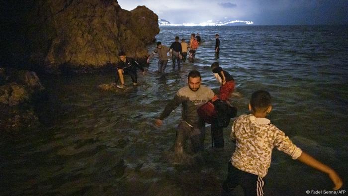 Los migrantes caminan en aguas poco profundas en Fnideq, Marruecos.