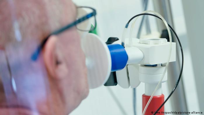 Ein Reha-Patient bläst in ein Testgerät für das Lungenvolumen