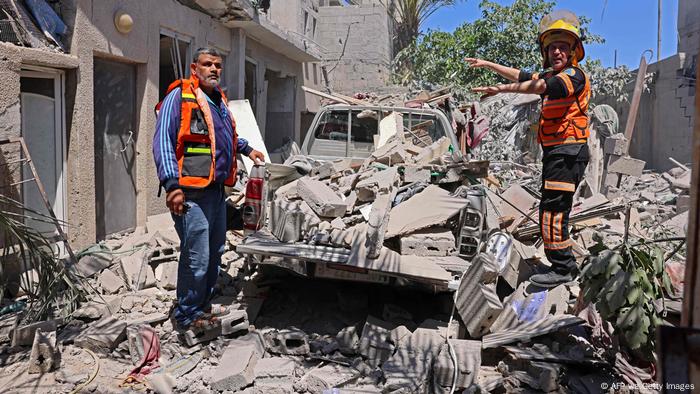 Homens de roupa de segurança em meio a destroços de edifício