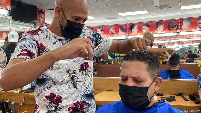 Customer wearing a mask has his hair cut by Moncado