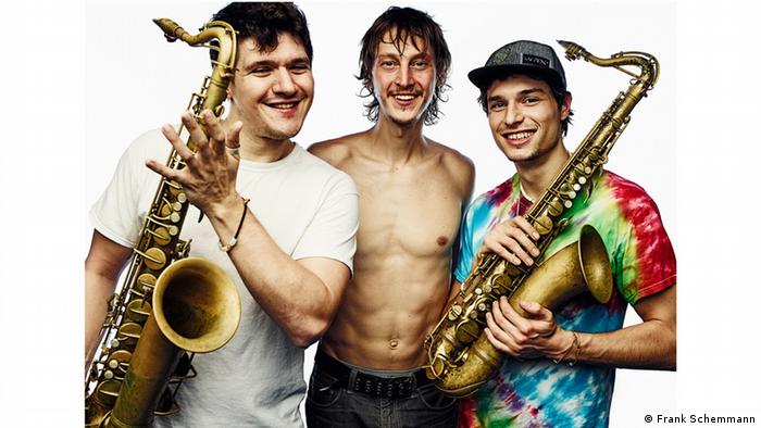 Mit ihren Saxophonen lächeln die drei Musiker in die Kamera