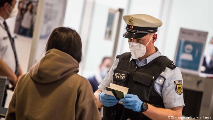 A federal police officer in the Munich International Airport checks the passport and documents of an arriving passenger