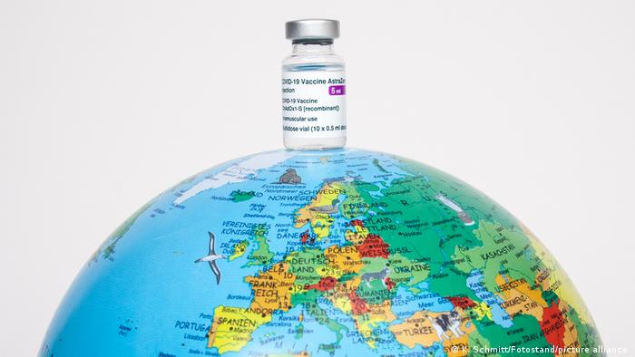 A small container of vaccine perched on a globe