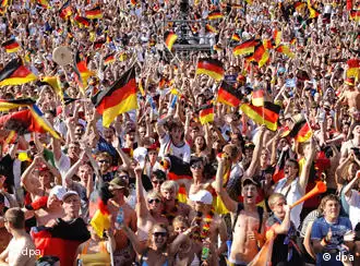 A crowd of German fans wave flags and celebrate