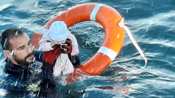 A member of the civil guard rescues a baby that was separated from its parents, who were migrants, in the sea off Ceuta, Spain