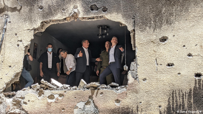 Eine Männergruppe blickt durch ein Loch in der Wand eines zerstörten Wohnhauses in Israel