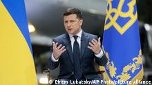 Ukrainian President Volodymyr Zelenskyy gestures while speaking to the media during a news conference with the world's largest airplane, Ukrainian Antonov An-225 Mriya in the background, at the Antonov aircraft factory in Kyiv, Ukraine, Thursday, May 20, 2021. (AP Photo/Efrem Lukatsky)