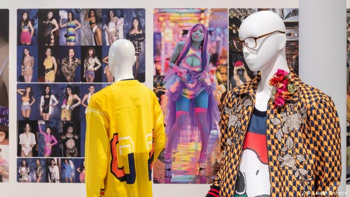 Two mannequins in colorful clothes, photos of various models in the background.