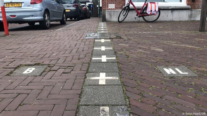 White crosses marking the border in Baarle, with 'B' for Belgium on one side, and 'NL' for Netherlands on the other
