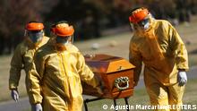 Ernesto Fabian Aguirre, a gravedigger in the Memorial cemetery, carries a coffin with his coworkers wearing protective equipment during an exercise for coronavirus disease (COVID-19) burials, after deaths have surpassed 70,000 amid a strong second wave of the pandemic and a slow vaccination process, in Buenos Aires, Argentina May 17, 2021. Picture taken May 17, 2021. REUTERS/Agustin Marcarian