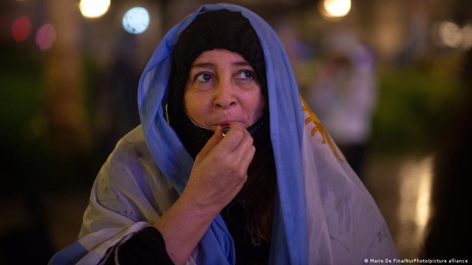 A protester in an Argentina flag blows a whistle.
