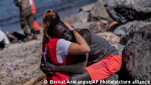 A migrant is comforted by a member of the Spanish Red Cross near the border of Morocco and Spain, at the Spanish enclave of Ceuta, on Tuesday, May 18, 2021. Ceuta, a Spanish city of 85,000 in northern Africa, faces a humanitarian crisis after thousands of Moroccans took advantage of relaxed border control in their country to swim or paddle in inflatable boats into European soil. The migrant was sent back to Morocco by Spanish security forces. (AP Photo/Bernat Armangue)