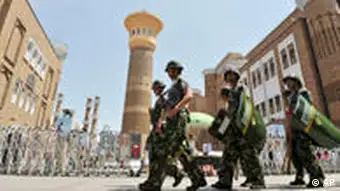 Paramilitary policemen and security workers patrol outside the Grand Bazzar in Urumqi, in northwest China's Xinjiang region, Monday, July 5, 2010. Teams of police patrolled streets in the western region of Xinjiang on Monday as stringent security was imposed for the one-year anniversary of China's worst ethnic violence in decades. (AP Photo) ** CHINA OUT **