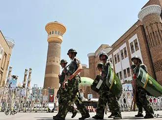 Paramilitary policemen and security workers patrol outside the Grand Bazzar in Urumqi, in northwest China's Xinjiang region, Monday, July 5, 2010. Teams of police patrolled streets in the western region of Xinjiang on Monday as stringent security was imposed for the one-year anniversary of China's worst ethnic violence in decades. (AP Photo) ** CHINA OUT **
