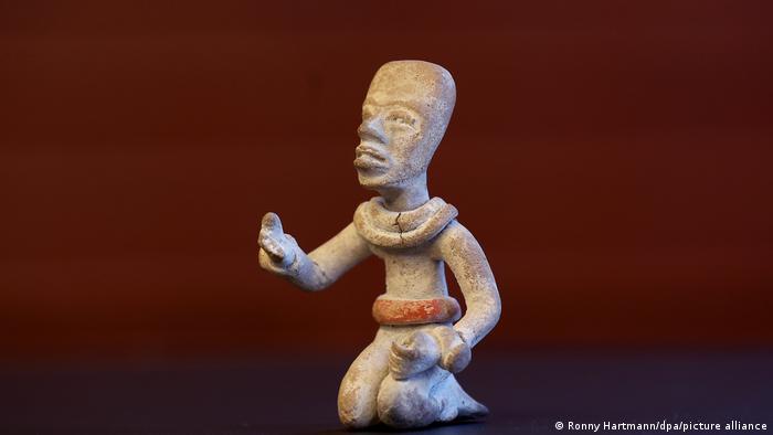 Eine Maya-Skulptur zeigt einen Menschen, der auf dem Boden kniet und die Hand ausstreckt