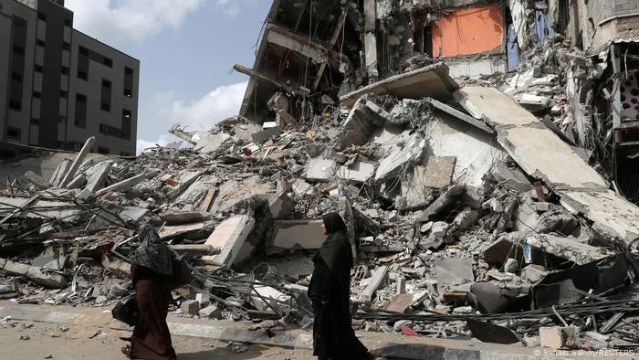 Mulheres palestinas passam pelas ruínas de um prédio em Gaza destruído em um ataque aéreo israelense. Mulheres palestinas passam pelas ruínas de um prédio em Gaza destruído em um ataque aéreo israelense.