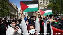 22.05.2021, Frankreich, Paris: Demonstrantinnen halten Schilder, auf denen die palästinensische Flagge abgebildet ist, während einer Kundgebung in Solidarität mit Palästina. Unter Vermittlung Ägyptens haben sich Israel und die im Gazastreifen herrschende Hamas nach elf Tagen militärischen Schlagabtauschs am 21.05.2021 auf eine Waffenruhe verständigt. Foto: Thibault Camus/AP/dpa +++ dpa-Bildfunk +++