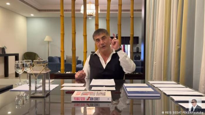 Screenshot Youtube | Mafiaboss Sedat Peker an einem Tisch in einem Raum der an eine luxoriöse Hotelsuite erinnert
