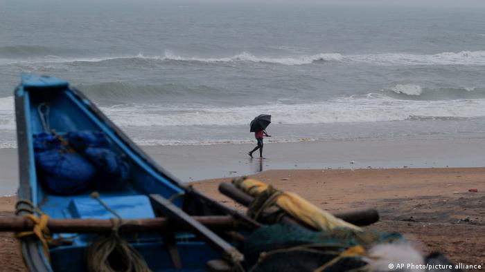 A man walks holding an umbrella during a drizzle at the Puri beach on the Bay of Bengalcoast in Odisha, India